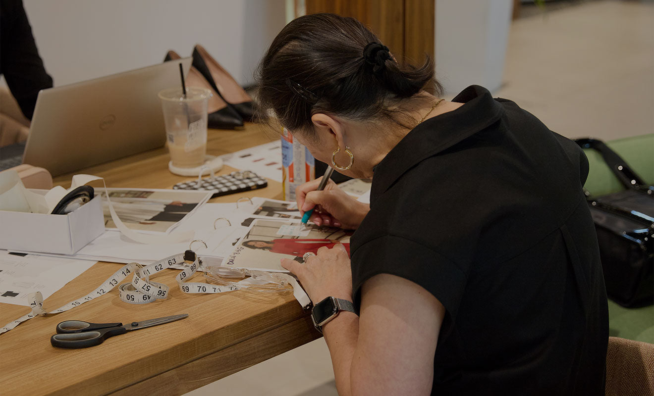 A merchandiser reviewing sales performance and swatches at her desk